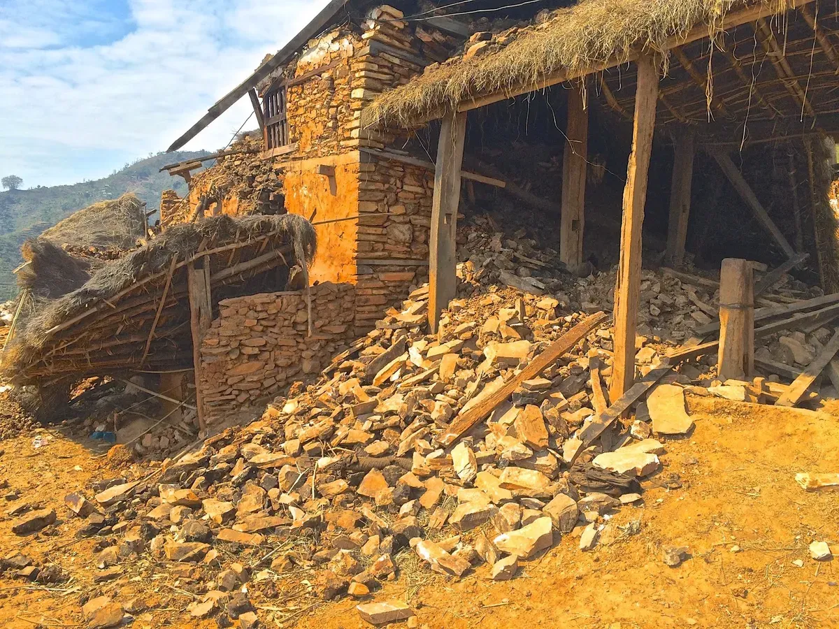 Collapsed stone walls beneath a thatched roof in Thumka