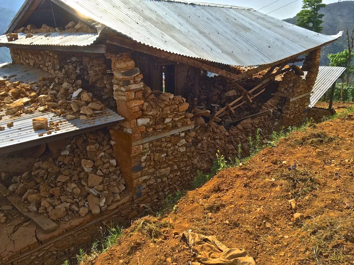Cracked stone wall beneath a corrugated metal roof