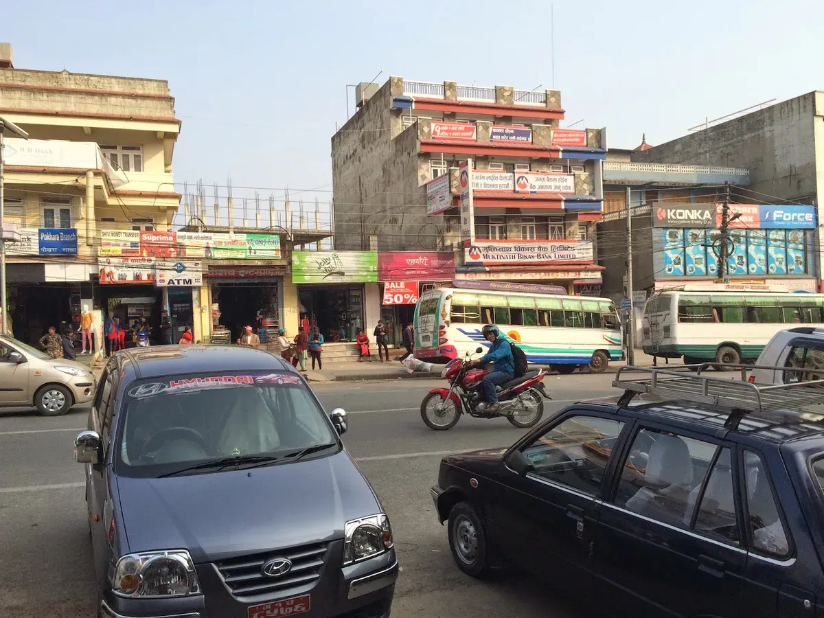 Motorcyclist passing shops on a street in Pokhara