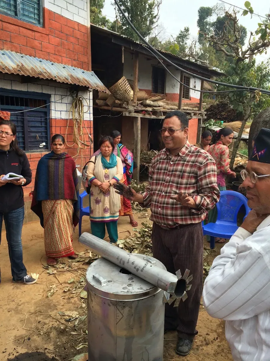 People gathered around a metal drum for a biochar demonstration